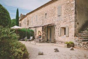 een stenen gebouw met een tafel en stoelen ervoor bij Rodin - Mas De Rey in Arpaillargues-et-Aureillac