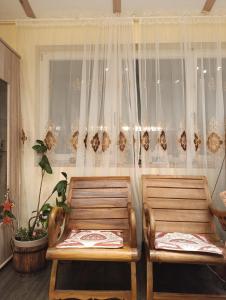 zwei Holzstühle vor einem Fenster mit Vorhängen in der Unterkunft Dahai Ferienwohnung Seebad Warnemünde Schulstraße 1, OG in Rostock