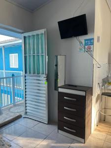 cocina con nevera y TV en la pared en Pousada Cantinho Azul Qt 03, en Passo de Torres