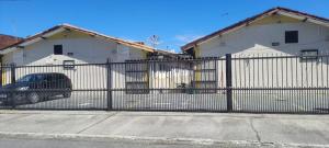 a fence with a car parked in front of a house at Flórida House in Praia Grande +2 photos