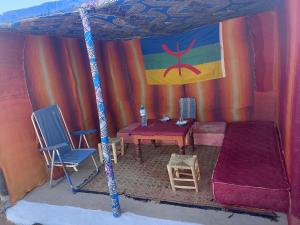 a tent with a bed and a table and chairs at Travel Oasis Merzouga Camp in Merzouga