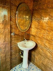 une salle de bains avec un lavabo blanc et un miroir dans l'établissement Essérè Mabia hôtel E-M, à Brazzaville 5 autres photos