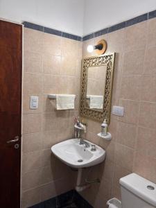 ein Badezimmer mit Waschbecken, Spiegel und Toilette in der Unterkunft El Descanso in Concepción