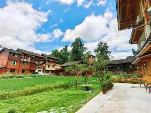 a resort with a green lawn and buildings at Xijiang Longtang Liyuan Mountain Resort B&B in Leishan +13 photos