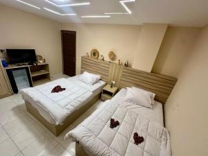 ein Schlafzimmer mit zwei Betten und einem Fernseher darin in der Unterkunft pumaa pyramids giza INN in Kairo