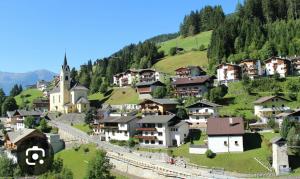 un pueblo en una colina con casas y una iglesia en Ferienwohnung Eichhorner, en Außervillgraten