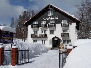 un edificio blanco con techo negro en la nieve en Orchidea, en Szklarska Poręba