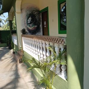 a building with a white railing and a painting on the wall at One love guest house morjim in Arambol