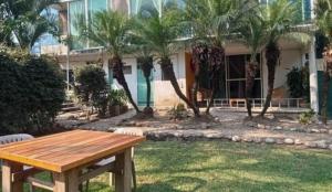 a picnic table in front of a building with palm trees at Lago24 Habitaciones in Cocoyoc