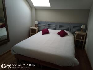 une chambre avec un grand lit blanc avec des oreillers rouges dans l'établissement Cottage Les Quatre Saisons, à Giverny