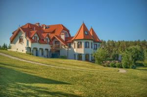 a large house on top of a grassy hill at Pensjonat Rybical in Ryn