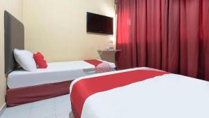 2 Betten in einem Hotelzimmer mit roten Vorhängen in der Unterkunft Hotel Hen Hen seven days rent in Kampong Saleng