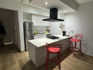 a kitchen with two red bar stools and a refrigerator at New Sweet Home Soukra in Sukrah