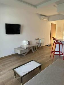 a living room with a table and a tv on a wall at New Sweet Home Soukra in Sukrah