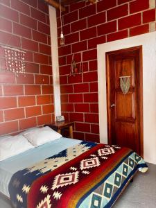 Ein Schlafzimmer mit roten Backsteinwänden und einem Bett mit einer bunten Decke in der Unterkunft Free Spirit Ecuador, Puerto Engabao in Engabao