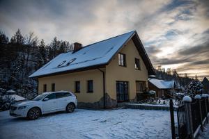 a white car parked in front of a house in the snow at Kwatery prywatne u Danusi in Wierchomla Wielka