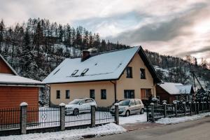 a house with two cars parked in the snow at Kwatery prywatne u Danusi in Wierchomla Wielka
