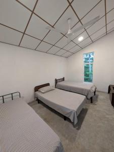 3 Betten in einem Zimmer mit weißen Wänden in der Unterkunft Andy Home Stay, Balapitiya in Balapitiya