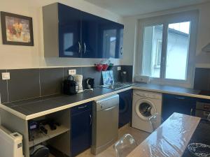 a kitchen with blue cabinets and a washing machine at Appartement charmant à Luzenac - 60m² - Confort moderne in Luzenac