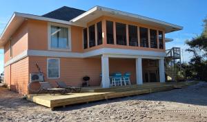 ein Haus mit einer Terrasse mit Stühlen und einem Tisch in der Unterkunft Tequila Sunrise in Pensacola