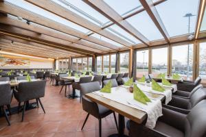 ein Esszimmer mit Tischen und Stühlen und Fenstern in der Unterkunft Hotel Momentum in Anif