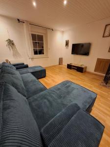 un salon avec un canapé bleu et une télévision à écran plat dans l'établissement Les Renards du Val, à Val-et-Châtillon