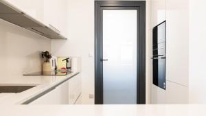 a kitchen with white counters and a black door at SUNSET SAILORS vibe apartment in Benidorm