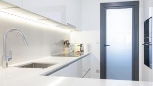 a white kitchen with white counters and a sink at SUNSET SAILORS vibe apartment in Benidorm