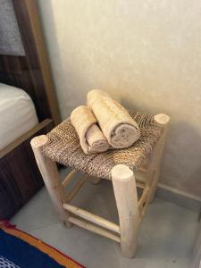 a bamboo stool with towels on it in a bedroom at taghoba surf house in Tamraght Ouzdar +44 photos