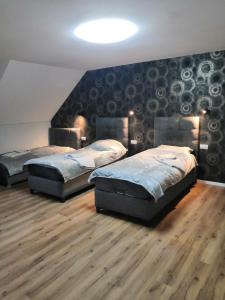 two beds in a room with wood floors and a wall at Pension bei Laura in Schwerte