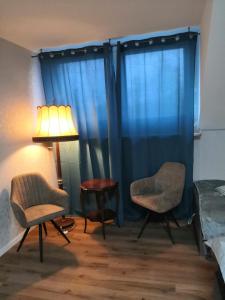 a bedroom with blue curtains and two chairs and a lamp at Pension bei Laura in Schwerte