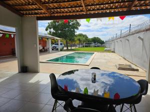 une table et des chaises dans un patio avec piscine dans l'établissement Chácara Urbana, à Juazeiro