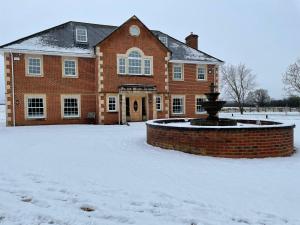 ein Backsteinhaus mit einem Brunnen im Schnee in der Unterkunft Meadow Farm in Royal Wootton Bassett