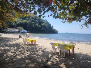 - un groupe de tables et de chaises sur la plage dans l'établissement Pousada Dádiva Encanto da Orquídea a passos da praia do Pontal c ar e frigobar, à Parati