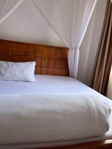 a bedroom with a bed with white sheets and curtains at Ashok Apartments APT C in Buzzi