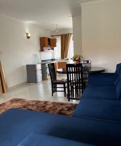 a living room with a blue couch and a kitchen at Ashok Apartments APT C in Buzzi +4 photos