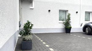 a white building with two potted plants in a parking lot at Ideale City-Wohnung mit 2 Schlafzimmern & Parking in Dortmund
