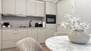 a white kitchen with a table and a vase with flowers at Ideale City-Wohnung mit 2 Schlafzimmern & Parking in Dortmund
