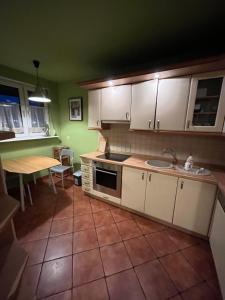 una cucina con mobili bianchi, un lavandino e un tavolo di Trzy Pokoje Park Śląski a Siemianowice Śląskie