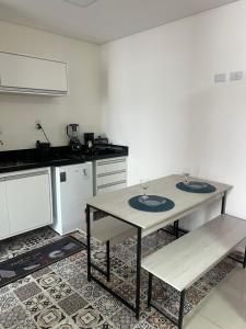 a kitchen with a table with two wine glasses on it at Flat Palladium in São Vicente