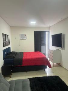a bedroom with a red bed and a tv at Flat Palladium in São Vicente +2 photos
