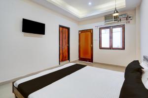 Un dormitorio con una cama y un televisor en la pared. en Hotel O NEW CLARK INN & BANQUET, en Bādshāhnagar