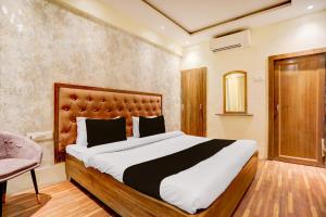 a bedroom with a large bed and a chair at Hotel O Gangay in Prayagraj