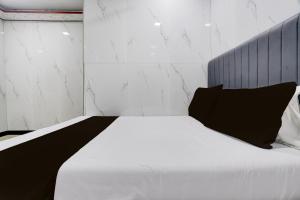 a bedroom with a white bed with a black pillow at Hotel O SR Residency in Mumbai