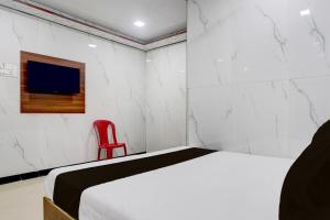 a bedroom with a bed and a red chair at Hotel O SR Residency in Mumbai