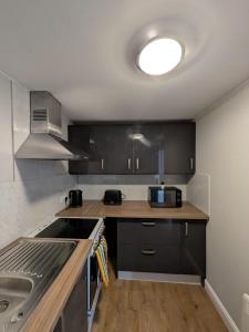 eine Küche mit schwarzen Schränken und einer Spüle in der Unterkunft Bright Comfortable 1 Bedroom Flat in Neepsend + 11 Fotos