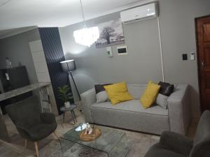 a living room with a gray couch and yellow pillows at Waterfall Deluxe in Rustenburg