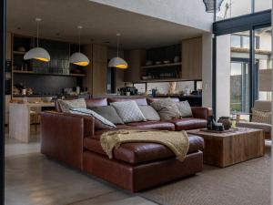 Izakithi River Villa في ماليلين: غرفة معيشة مع أريكة بنية ومطبخ