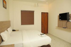 Un dormitorio con una cama blanca y un televisor. en Redfox Service Apartment DLF, en Chennai 21 fotos más