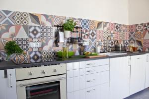 a kitchen with white cabinets and geometric tiles on the wall at Chillout Hostel in Warsaw